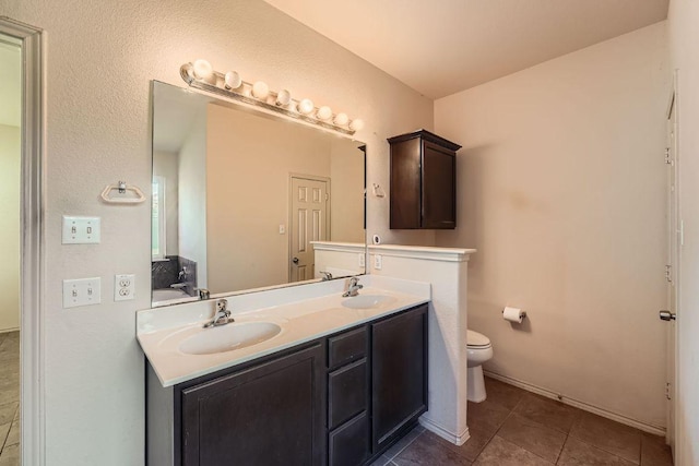 full bathroom with toilet, tile patterned flooring, double vanity, and a sink