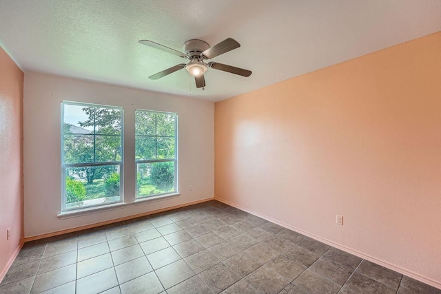 spare room with a ceiling fan and baseboards