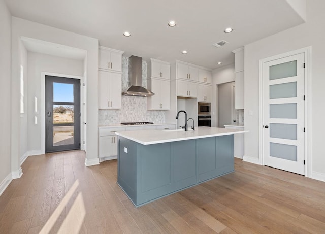 109 Flora Springs Cv, Liberty Hill, TX 78642 - kitchen with wall chimney range hood, a sink, stainless steel microwave, light wood-style floors, and oven