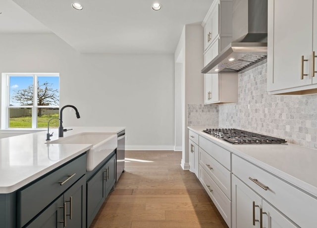 109 Flora Springs Cv, Liberty Hill, TX 78642 - kitchen with wall chimney range hood, stainless steel appliances, a sink, baseboards, and recessed lighting