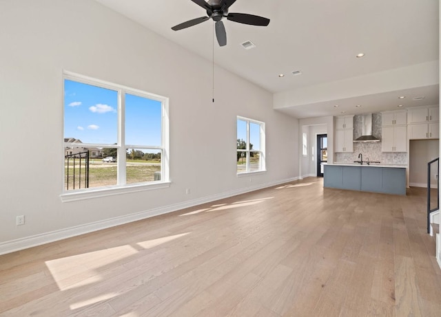 109 Flora Springs Cv, Liberty Hill, TX 78642 - unfurnished living room featuring light wood finished floors, healthy amount of natural light, a ceiling fan, a sink, and recessed lighting