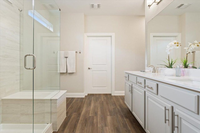 full bathroom with baseboards, a stall shower, wood finished floors, and visible vents