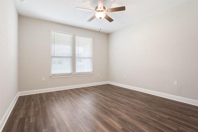 unfurnished room featuring baseboards, ceiling fan, and dark wood finished floors