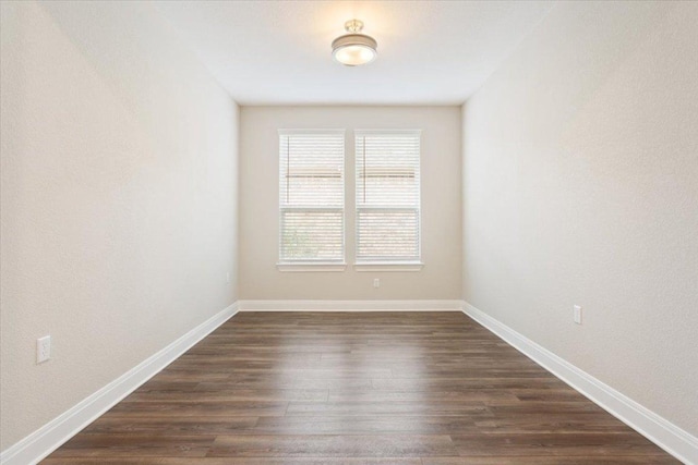 unfurnished room with baseboards and dark wood-style floors
