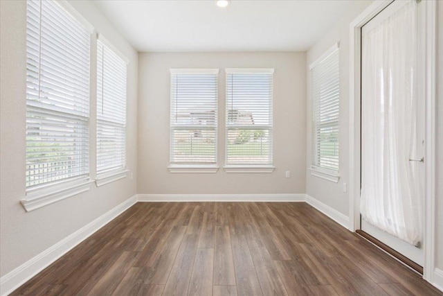 unfurnished room with baseboards and dark wood-style floors