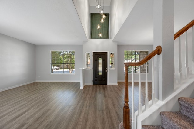 foyer with a towering ceiling, stairway, wood finished floors, and baseboards