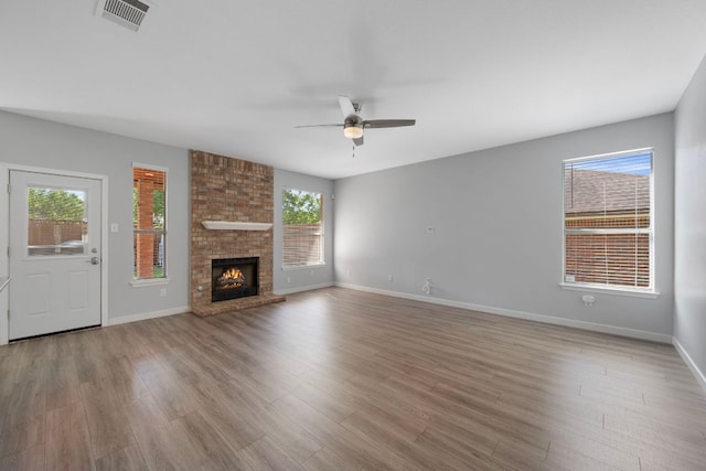 unfurnished living room with wood finished floors, visible vents, a ceiling fan, and baseboards