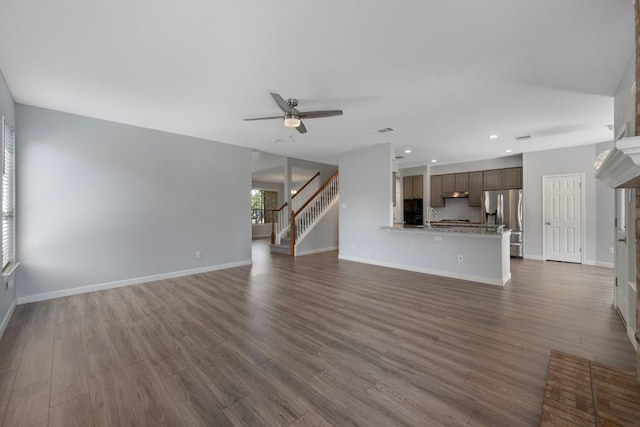unfurnished living room with recessed lighting, dark wood-style flooring, stairway, a ceiling fan, and baseboards