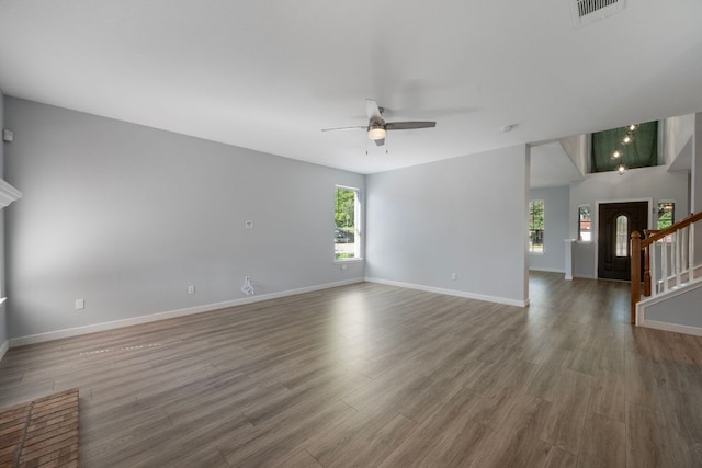 unfurnished living room with visible vents, ceiling fan, baseboards, wood finished floors, and stairs