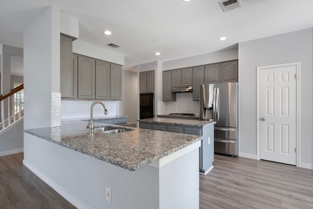 kitchen with a sink, appliances with stainless steel finishes, visible vents, a peninsula, and gray cabinets