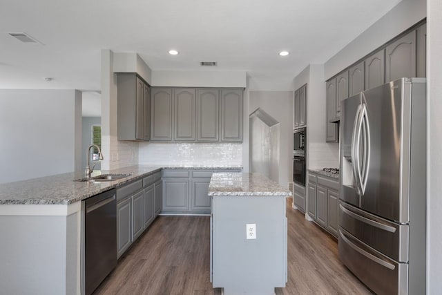 kitchen with a sink, gray cabinets, appliances with stainless steel finishes, and decorative backsplash
