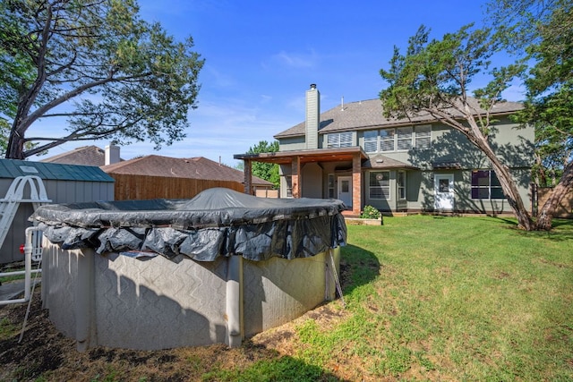 exterior space featuring fence, a covered pool, a yard, and a storage shed
