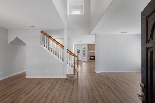 entryway with visible vents, stairway, wood finished floors, and a fireplace