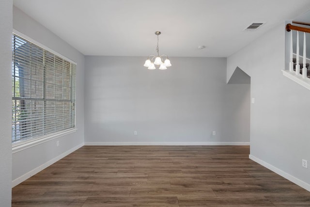 unfurnished dining area featuring visible vents, a notable chandelier, baseboards, and dark wood finished floors