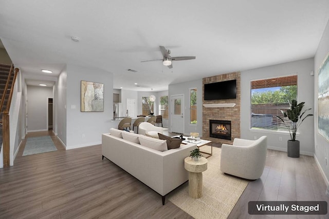 living room with ceiling fan, baseboards, a healthy amount of sunlight, and a fireplace
