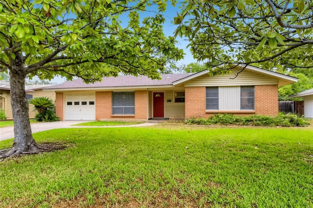 ranch-style house featuring brick siding, a front lawn, driveway, and an attached garage