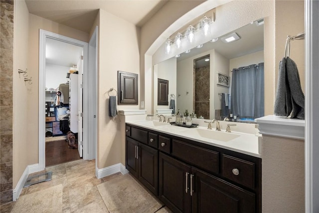 full bathroom with baseboards, a shower with curtain, double vanity, and a sink