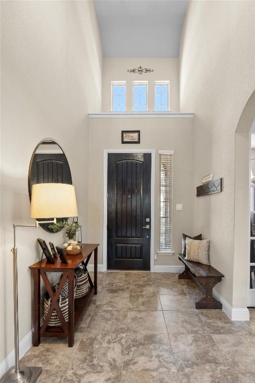foyer with a towering ceiling, arched walkways, and baseboards