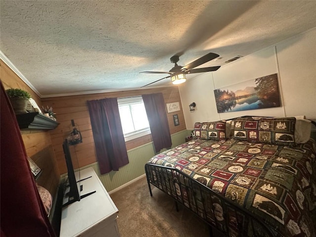 bedroom with a textured ceiling, visible vents, wooden walls, carpet, and a ceiling fan