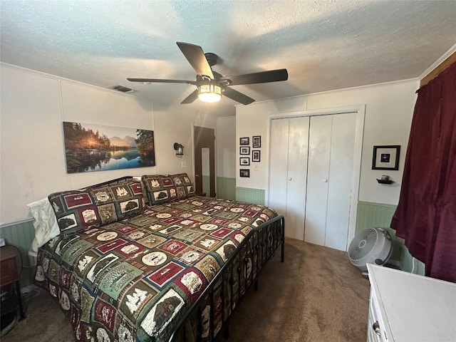 carpeted bedroom featuring a textured ceiling, visible vents, wainscoting, and a closet