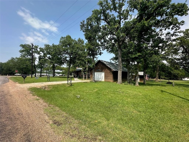 view of yard with a garage, an outbuilding, and driveway