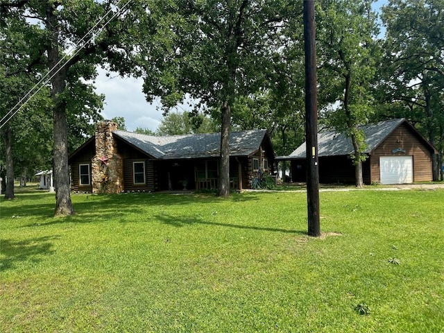 view of front facade with a chimney, a garage, a front yard, and log siding