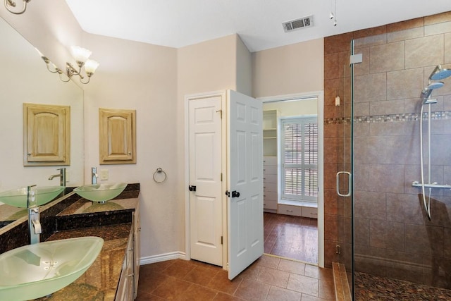 full bathroom with double vanity, a sink, a stall shower, and visible vents