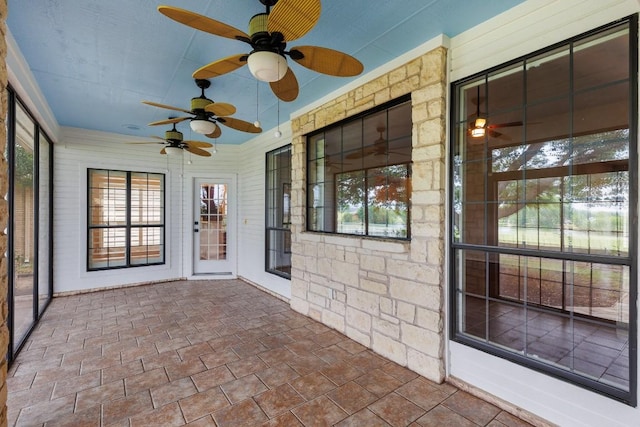 unfurnished sunroom featuring a ceiling fan
