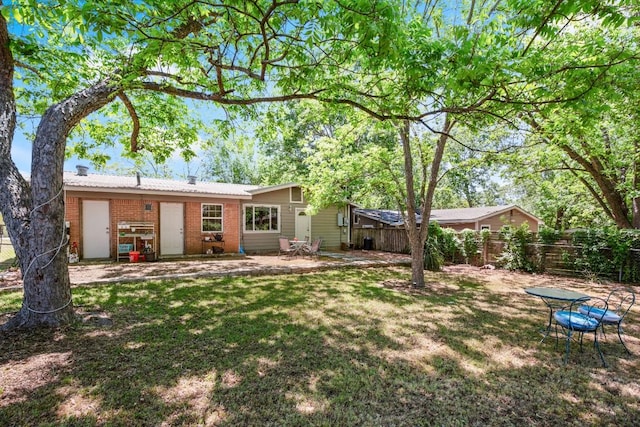 rear view of property featuring fence, a lawn, a patio, and brick siding