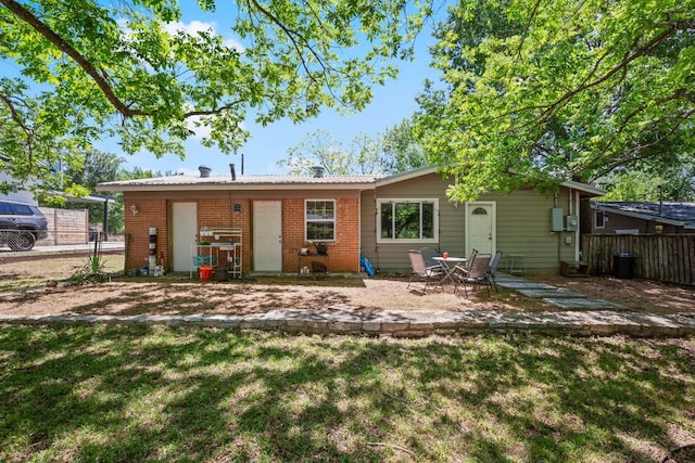 rear view of property with a patio, brick siding, fence, and a yard