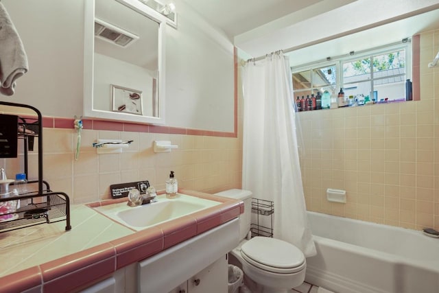 full bath with tile walls, shower / bath combo with shower curtain, toilet, vanity, and visible vents