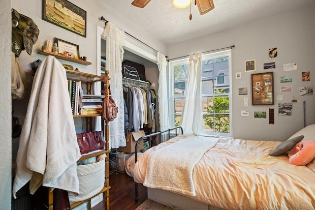 bedroom with a textured ceiling, wood finished floors, a ceiling fan, and a closet