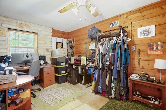 office area with a ceiling fan and wooden walls