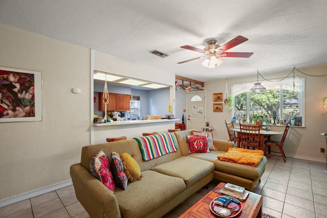 living area with light tile patterned floors, a ceiling fan, visible vents, and baseboards