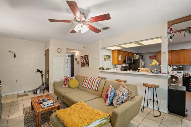 living area featuring visible vents, light tile patterned floors, ceiling fan, and washer / clothes dryer