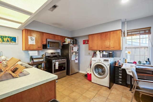 kitchen with light countertops, brown cabinets, appliances with stainless steel finishes, and washer / clothes dryer