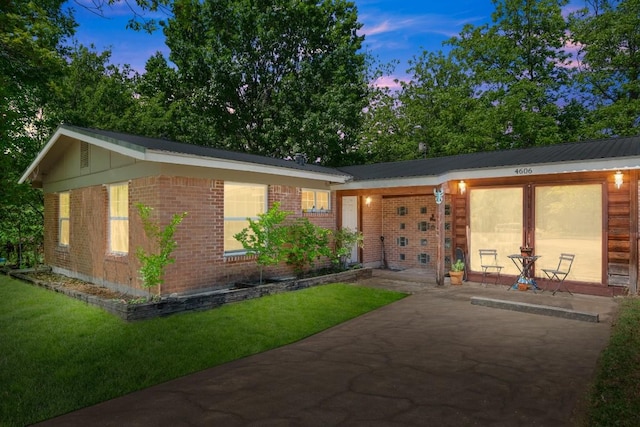 ranch-style house featuring a lawn, a patio area, and brick siding