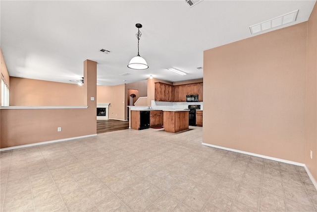 2049 Rachel Ln, Round Rock, TX 78664 - kitchen with black appliances, open floor plan, brown cabinetry, light countertops, and decorative light fixtures