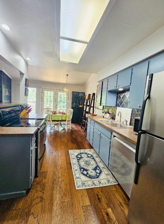 kitchen featuring a sink, blue cabinets, stainless steel appliances, and dark wood finished floors