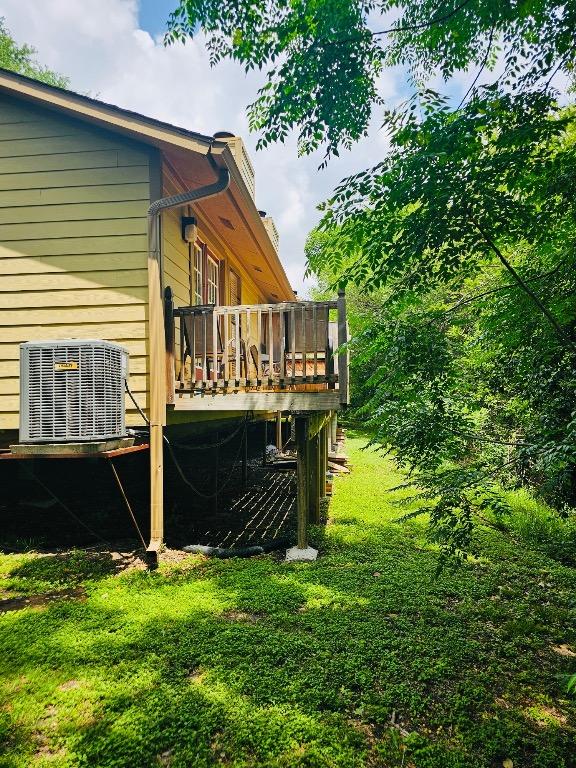 rear view of house featuring a lawn, a deck, and central AC
