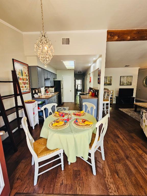 dining area with visible vents, ornamental molding, a notable chandelier, and dark wood-style flooring