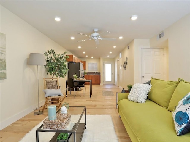 living area featuring a ceiling fan, visible vents, baseboards, and light wood-style floors