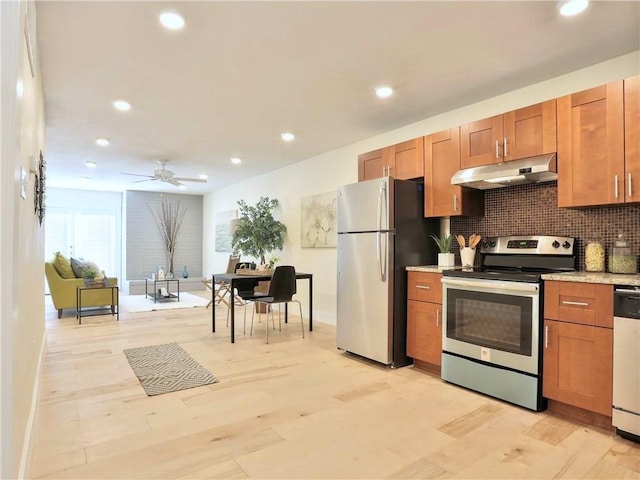kitchen with stainless steel appliances, light wood-style floors, under cabinet range hood, brown cabinetry, and backsplash