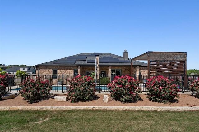rear view of house with fence, brick siding, and solar panels