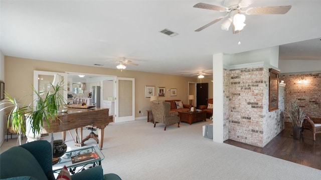 living room with visible vents, a ceiling fan, brick wall, and light colored carpet