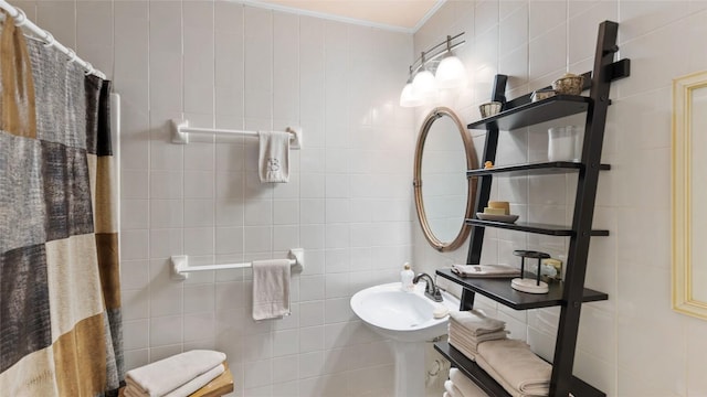 full bathroom with a sink, a shower with curtain, ornamental molding, and tile walls