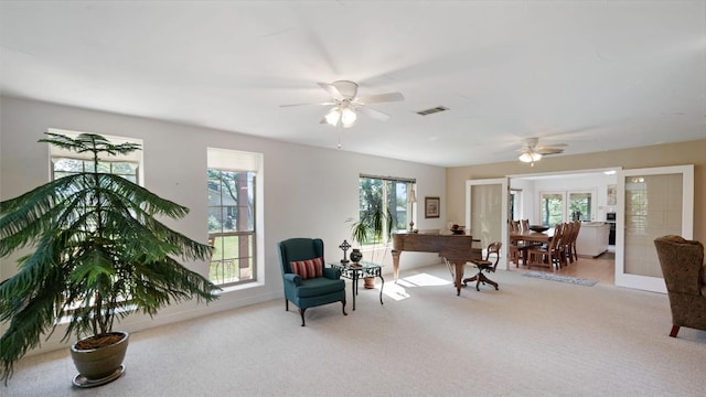 living area featuring a ceiling fan, visible vents, carpet floors, and baseboards