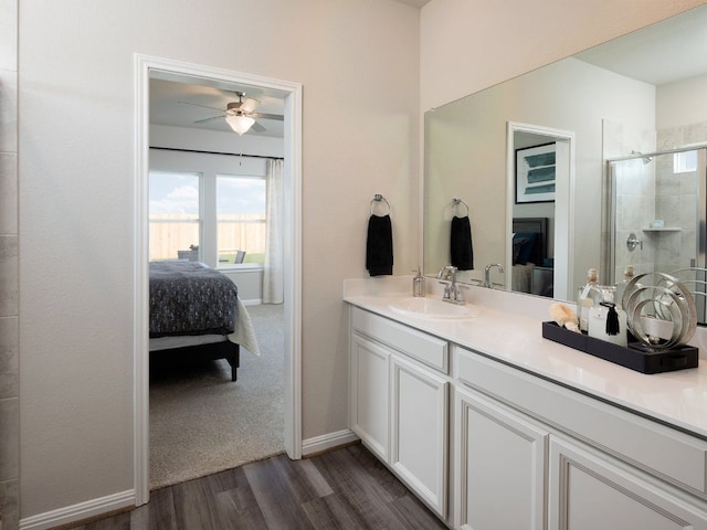 ensuite bathroom with wood finished floors, ensuite bathroom, vanity, a stall shower, and a ceiling fan
