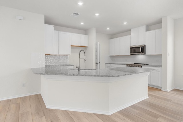 121 Coastal Way, Georgetown, TX 78628 - kitchen with stainless steel appliances, a sink, a peninsula, light stone countertops, and light wood-style flooring