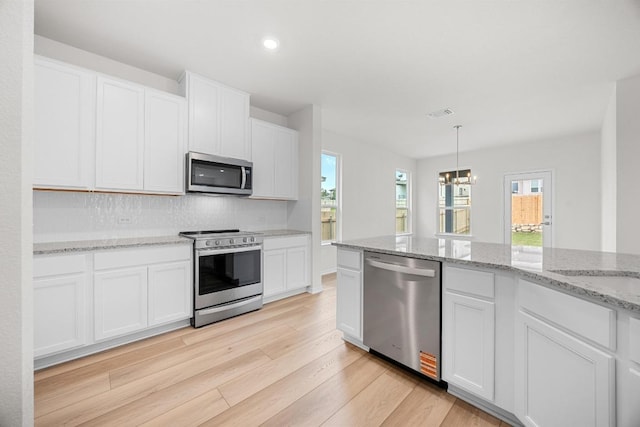 121 Coastal Way, Georgetown, TX 78628 - kitchen with stainless steel appliances, light wood finished floors, white cabinets, plenty of natural light, and recessed lighting